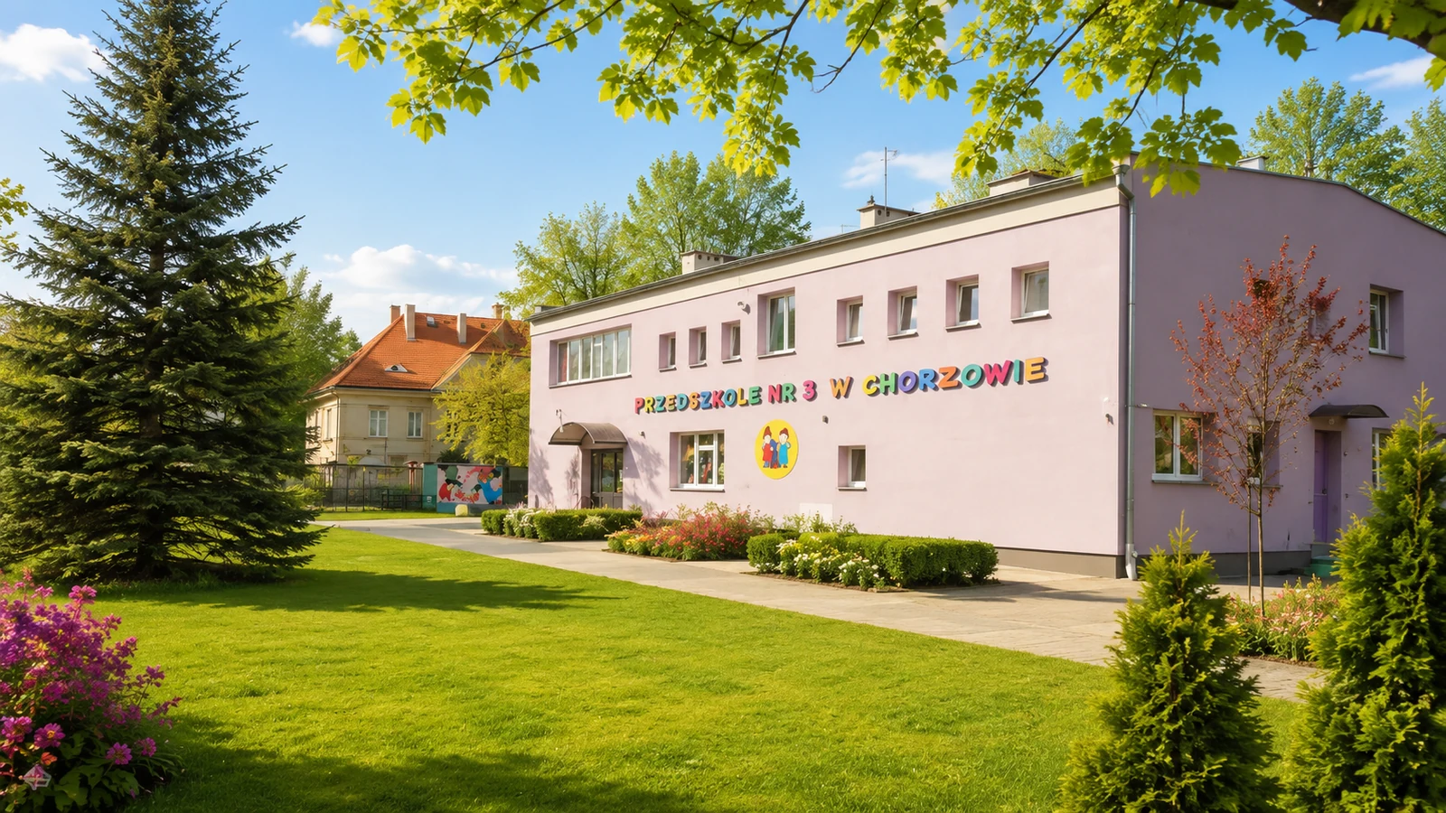 Budynek Przedszkola nr 3 w słoneczny dzień, otoczony zielenią i kwiatami